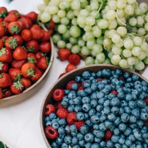 A vibrant assortment of fresh berries and grapes displayed on a white tablecloth, perfect for summer dining.